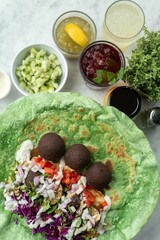 Close-up shot of ingredients for tortilla falafel wrap, with diced tomatoes, onions, jalapenos