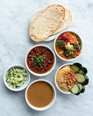 Assorted food for Mexican dinner, including flatbread, hummus, bean soup, cucumber and veggie soup