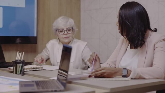 mulher Brasileira negra e sua sócia idosa discutindo o planejamento de orcamento da empresa delas no Brasil