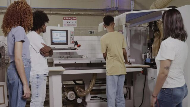 Brazilian teacher explaining to students how a machine works in a factory during a class at a technical school in Brazil