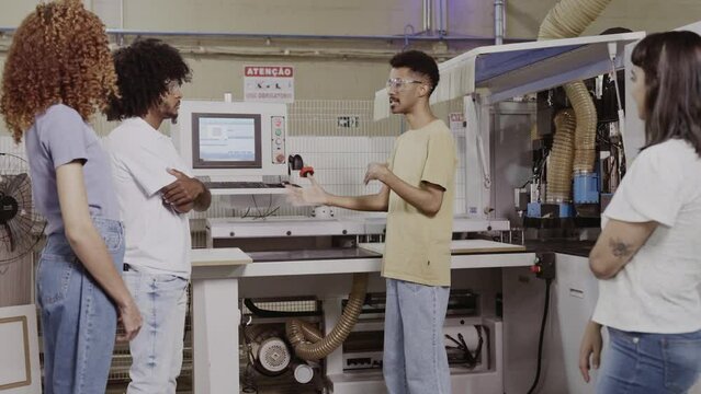 professor Brasileiro explicando para os alunos o funcionamento de uma m&aacute;quina em uma f&aacute;brica durante aula de uma escola t&eacute;cnica no Brasil
