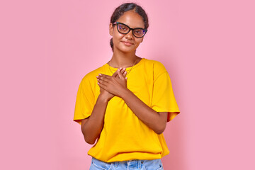 Young kind optimistic Indian woman millennial in glasses and casual clothes puts palms on chest...