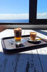 Hot drinks on a tray. A coffee with milk and a Barraquito or zaperoco coffee: a very popular sweet coffee drink in the Canary Islands made up of condensed milk, liquor, espresso coffee and foamed milk