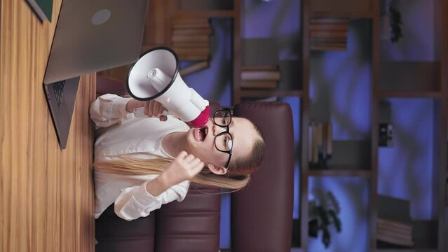 Angry severe child taking disciplinary action with team members for doing bad work. Vertical video of annoyed little lady yelling in loudspeaker during online video conference on laptop.
