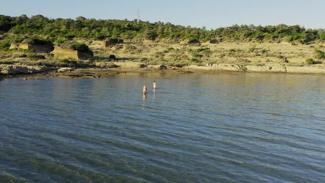 Two young women are walking in the shallow sea in Rab Island, Croatia