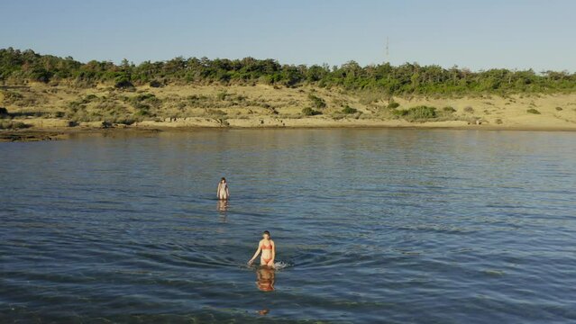 Two young women are walking in the shallow sea in Rab Island, Croatia