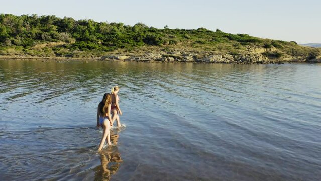 Two young women are walking in the shallow sea in Rab Island, Croatia