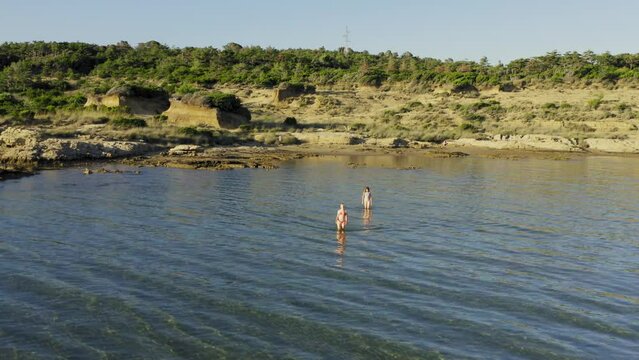 Two young women are walking in the shallow sea in Rab Island, Croatia