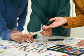 Group of application designers testing and discussing on new app features, collaborating on new project in office. UX UI design concept