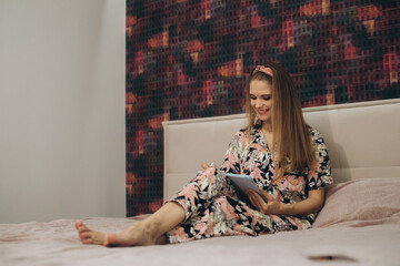 Blonde girl working on a tablet in bed