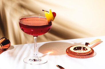 New Yorker red cocktail with whiskey, grenadine, bitter, lemon and ice garnished with lemon zest and cocktail cherry in glass. Beige background, hard light