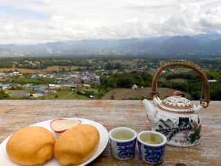 Set breakfast in morning. Chinese Kettle hot tea and Fried mantou (bread) with beautiful city mountain view in Pai province, northern of thailand. drink tea for healthy nourish the heart concept.