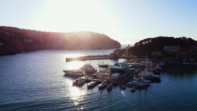 Drone footage over boats near Soller Port in the sea with green mountains at sunset in Mallorca