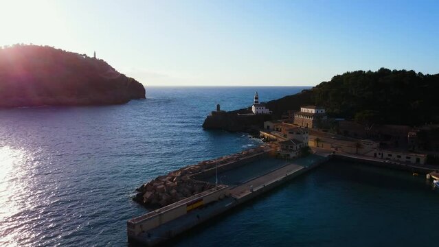 Drone footage over boats near Soller Port in the sea with green mountains at sunset in Mallorca
