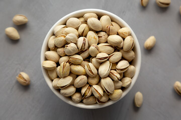 Salted and Roasted Pistachios in a Bowl on a gray background, top view. Overhead, from above, flat lay.