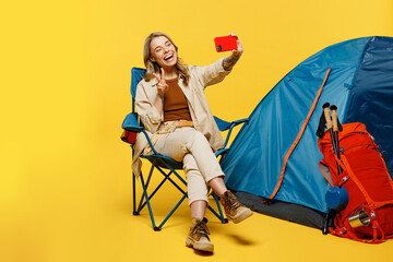 Full body young woman sit near bag stuff tent doing selfie shot mobile cell phone isolated on plain...