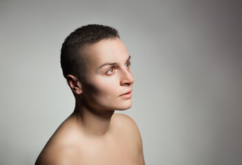 Fototapeta na wymiar portrait of young woman with short hair and bare shoulder on grey background