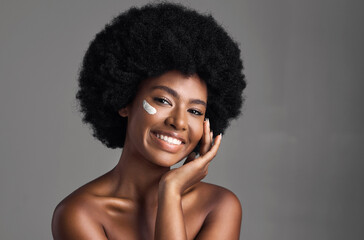 Black woman, cream on face and beauty with cosmetics product, skincare and dermatology on studio...