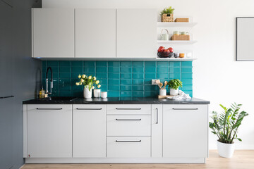 home kitchen with cozy interior, white cupboard and blue tiled wall
