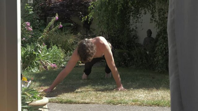 A fit young man doing archer pushups in backyard sunshine