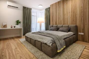 Double bed, table, wooden wall and large window in comfortable bedroom