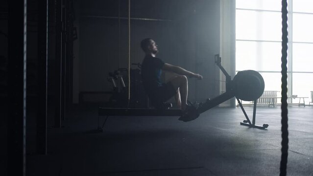 Athletic Man Doing Exercise In Gym, Using Rowing Machine For Developing Power Of Arms