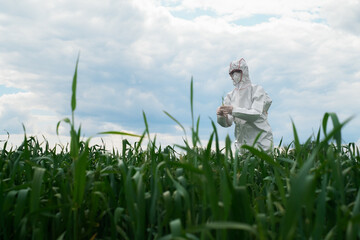 Gardener in a protective suit, mask and goggles uses a professional sprayer to treat the garden with insecticides and fungicides against pests