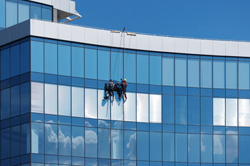 High-rise fitters repairing a glass panel in a window of a high-rise building.