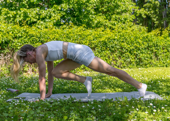 Fototapeta premium .A young, athletic girl is engaged in stretching in the fresh air. Beauty and health. Active lifestyle. Physical exercise. Fitness. Sport
