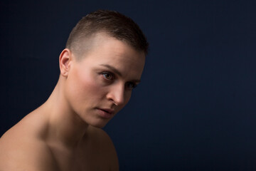 portrait of young woman with short hair and bare shoulder on blue background