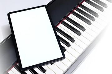 Naklejka premium Tablet with a white screen lying on a digital piano.