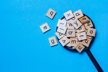 English alphabet made of square wooden tiles with the English alphabet scattered on blue...