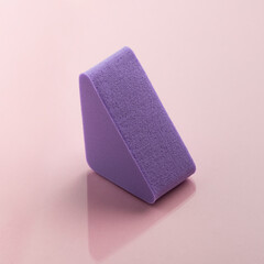 Purple cosmetic sponge on pink background