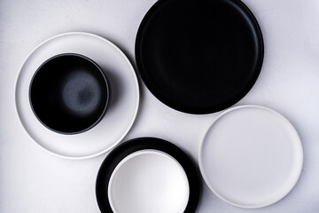 Fototapeta na wymiar Empty ceramic plate, black and white on a concrete white background. Stylish tableware
