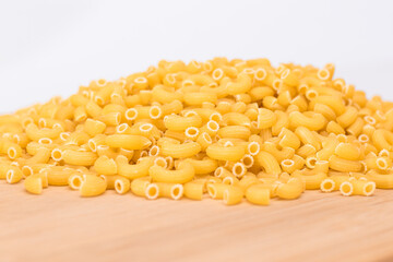 A Heap of Uncooked Chifferi Rigati Pasta on Wooden Kitchen Board. Fat and Unhealthy Food. Classic Dry Macaroni. Italian Culture and Cuisine. Raw Pasta