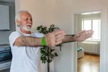 Senior man exercises with resistance band at home.