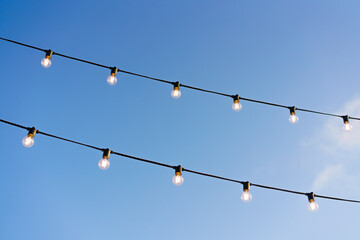 light bulbs on a wire against a blue sky, on a sunny day, lighting for a festive mood