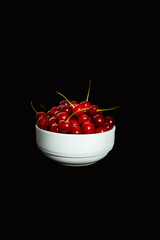 Cherries in a white plate on a black background