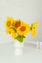 A bouquet of sunflowers in a vase are on the table