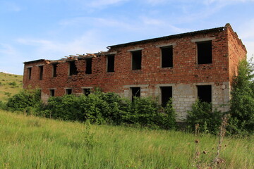 Fototapeta na wymiar A dilapidated brick building in a grassy field