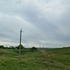 Obraz premium A field with grass and a pole with Codrington Wind Farm in the background