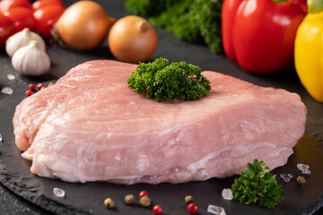 Fresh raw pork meat. A piece raw pork shoulder with spices and vegetables on a slate board. Pork tenderloin. Pulpa, carne de porc. 