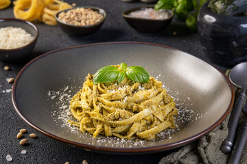Tagliatelle pasta with pesto sauce and fresh basil leaves. Close up. Paste cu sos pesto.