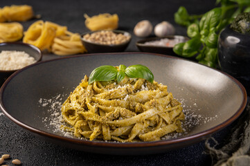 Tagliatelle pasta with pesto sauce and fresh basil leaves. Close up. Paste cu sos pesto.