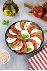 Italian caprese salad with tomatoes, mozzarella, basil on a gray background. Top view. Italian food. Copy space.