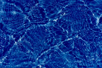 Blue water with ripples on the surface. Defocus blurred transparent blue colored clear calm water surface texture with splashes and bubbles. Water waves with shining pattern texture background.