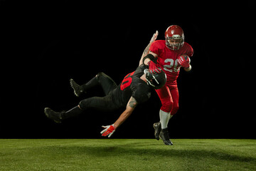 Fototapeta na wymiar Two competitive men, american football players in full uniform and equipment on field playing over black background. Concept of professional sport, action, lifestyle, competition, hobby, training, ad