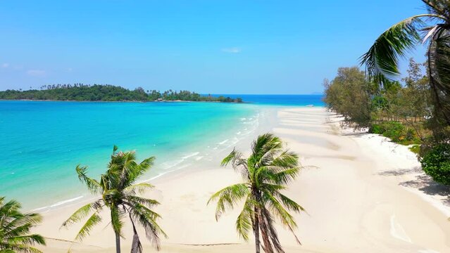 Amazing view of a tropical beach with white sand, turquoise ocean water, and coconut palm trees. An idyllic retreat on a paradise island in Thailand.