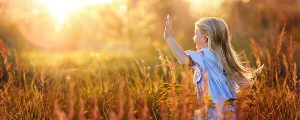 Happy child running across the field outdoors in bright sunlight. Sunny background
