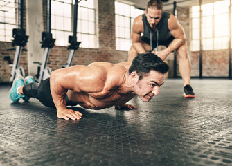 Fototapeta premium Fitness, personal trainer and athlete doing a push up exercise for strength, health and wellness. Sports, training and male person doing a body building arm workout with a coach for motivation in gym